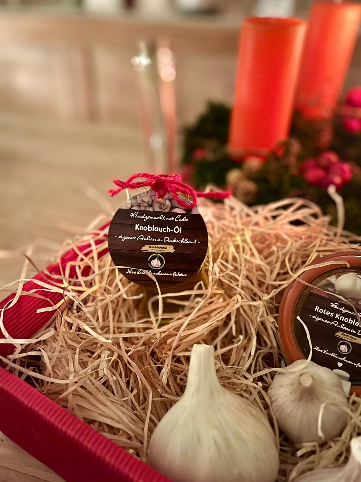 Geschenkkörbchen mit Knoblauch-Öl, Rotem Knoblauch-Pesto und Knoblauchknollen in Holzwolle, weihnachtlich dekoriert