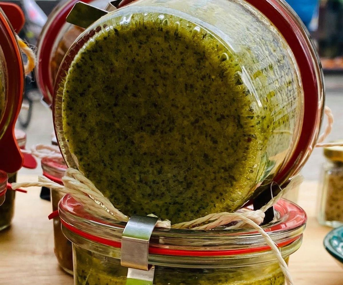 Weckglas mit Grünem Knobi-Pesto in Nahaufnahme, auf einem weiteren Glas liegend