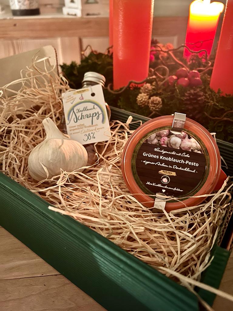 Herren-Gedeck: Knobi-Schnaps, Grünes Knoblauch-Pesto und Knoblauchknolle in Holzwolle einer Geschenkbox