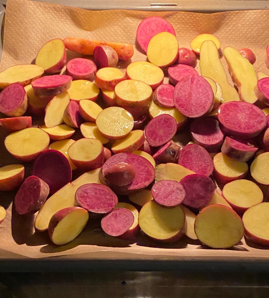 Halbierte Kartoffeln der Sorte Rosi mit rotem und gelbem Fleisch auf einem Backblech mit Backpapier